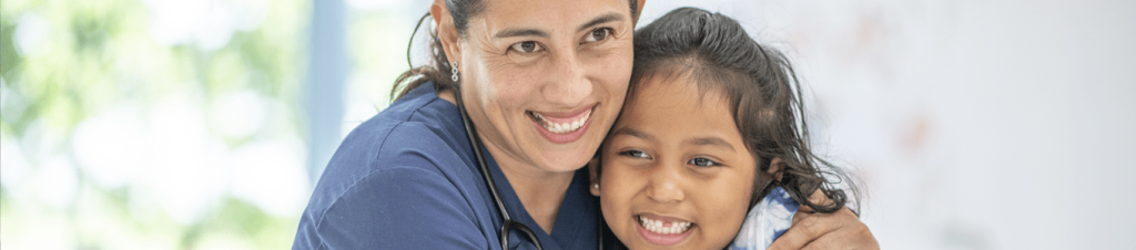 medical professional hugging child, both smiing
